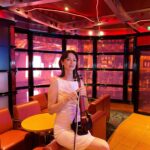 Professional female violinist in a white dress performing at an indoor event venue with warm ambient lighting.