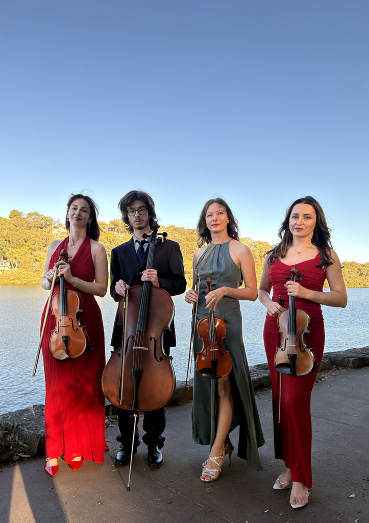 Professional string quartet with two violinists, a violist, and a cellist performing at an outdoor event.