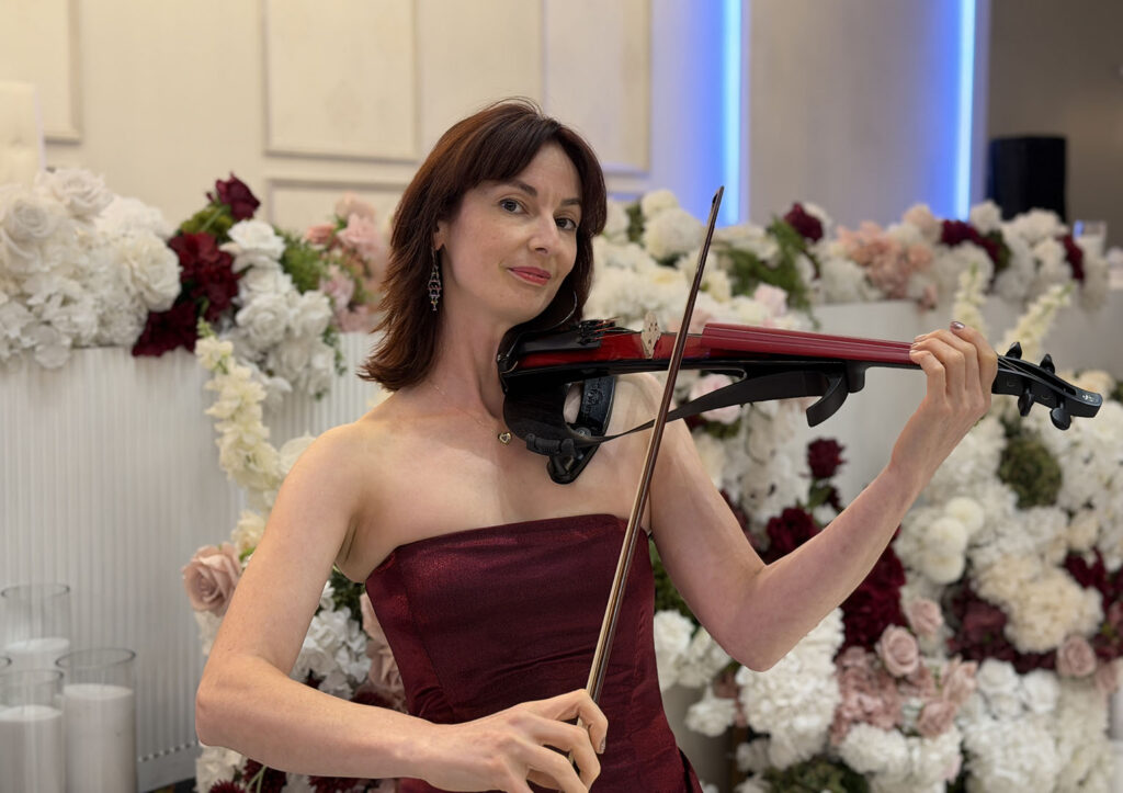 Professional solo violinist performing live at a wedding reception in Sydney, featuring elegant floral backdrop styling.
