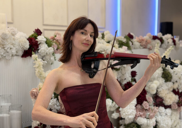 Professional solo violinist performing live at a wedding reception in Sydney, featuring elegant floral backdrop styling.