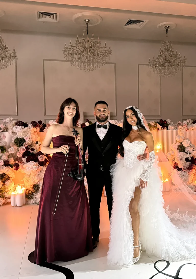 Bride and groom posing with a live violinist at an elegant luxury wedding reception.