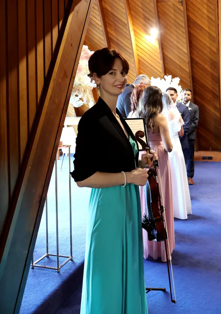 Solo female violinist holding a violin inside a high-ceiling chapel venue during a PlanEvent wedding ceremony.