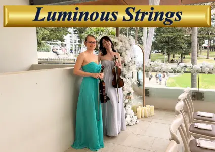 Two female musicians from Luminous Strings performing with a violin and cello at a bright outdoor event venue.